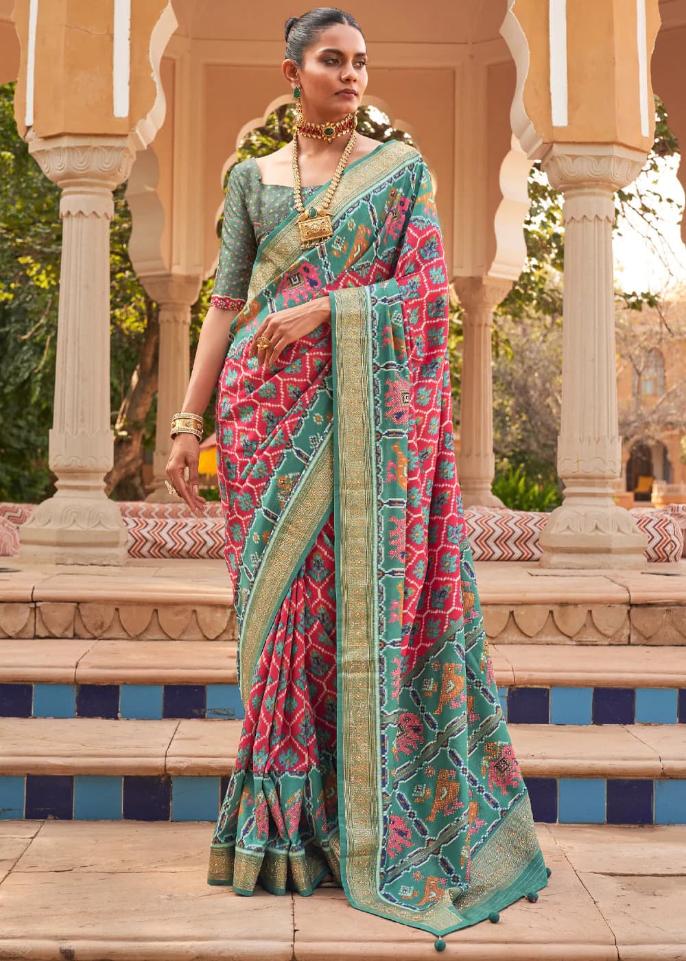 Close-up of the woven zari border and patola pattern on a teal and pink silk saree